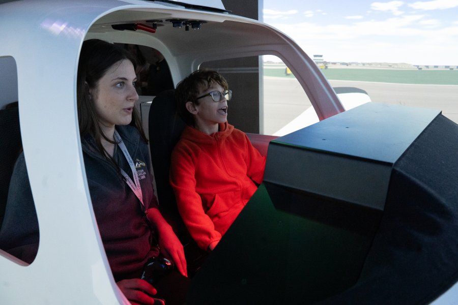 Grace Blackburn and Vail Fear sit inside a flight simulator.