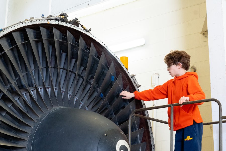 Vail Fear stands next to a large jet engine.