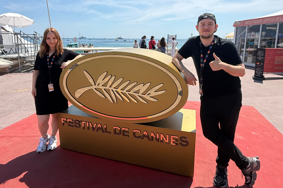 Laney Roberts and Sean Knowles stand next to the Cannes Film Festival Sign