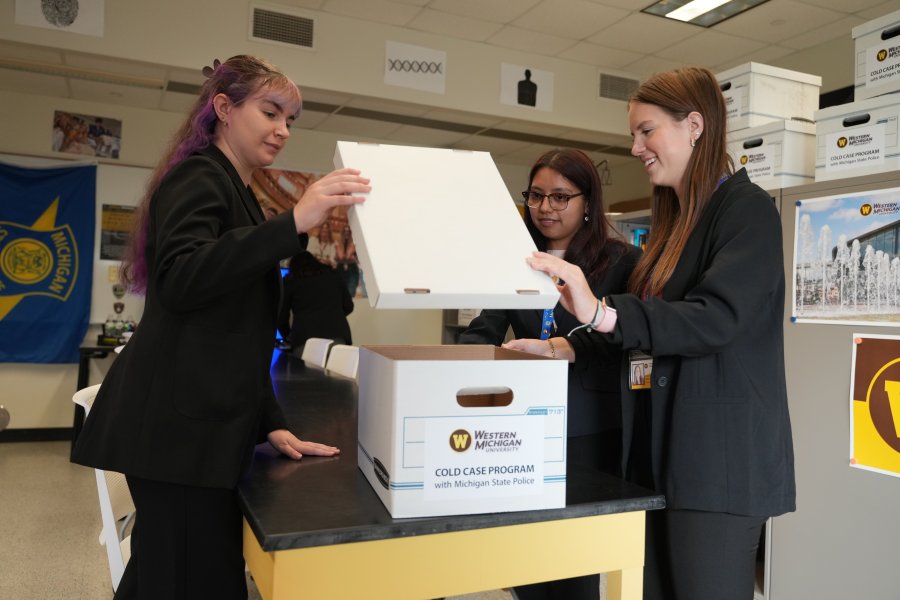 Students in the Cold Case Program open a box filed with criminal files.
