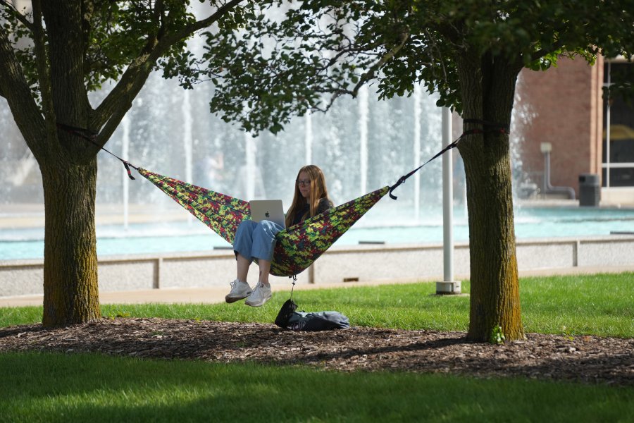 Student works on laptop in a hammock at Miller Fountain