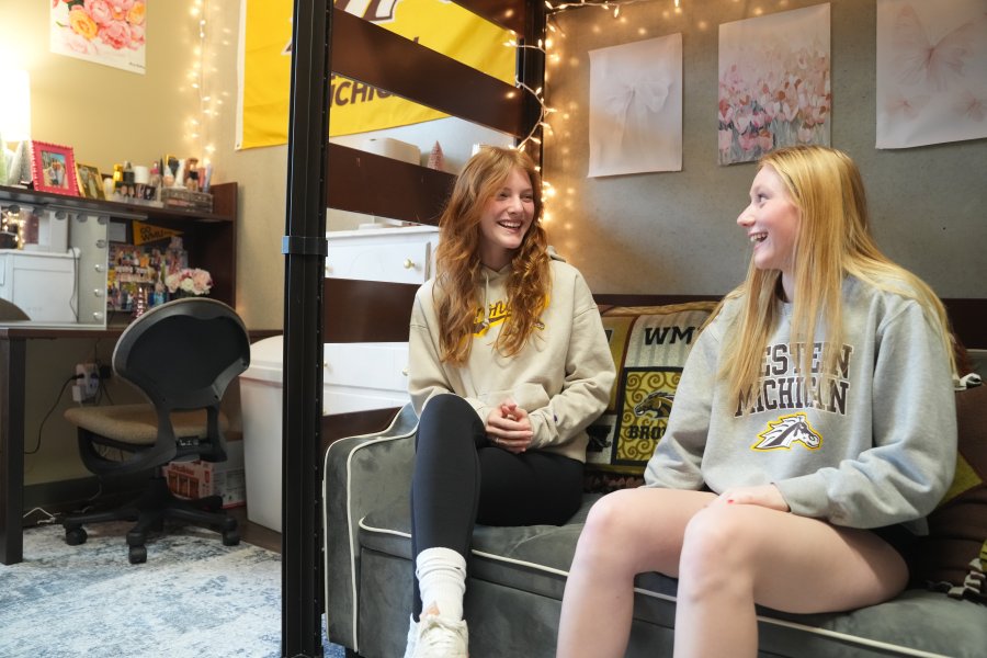 Two students pose smiling in their residence hall room.