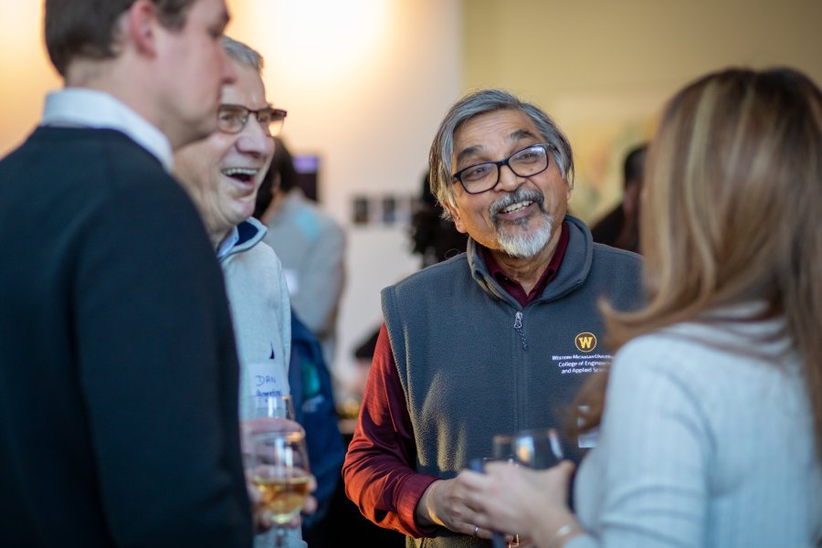 A faculty member speaks with people at a reception.