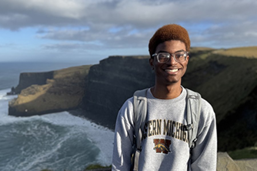 A student standing in front of a scenic cliffside