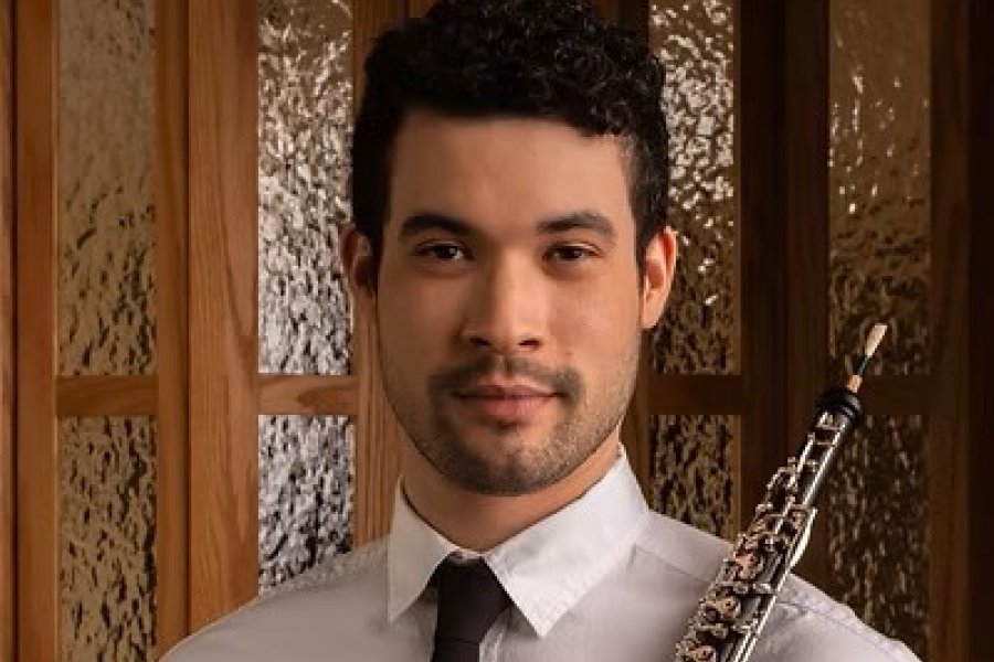 A man in a white shirt and black tie holding an oboe.