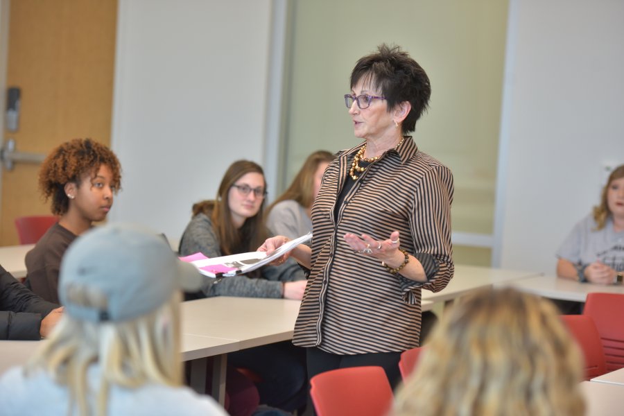 Professor engaging in conversation with students during class. 