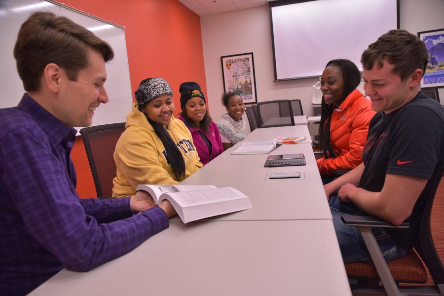 Students and faculty review a text book. 