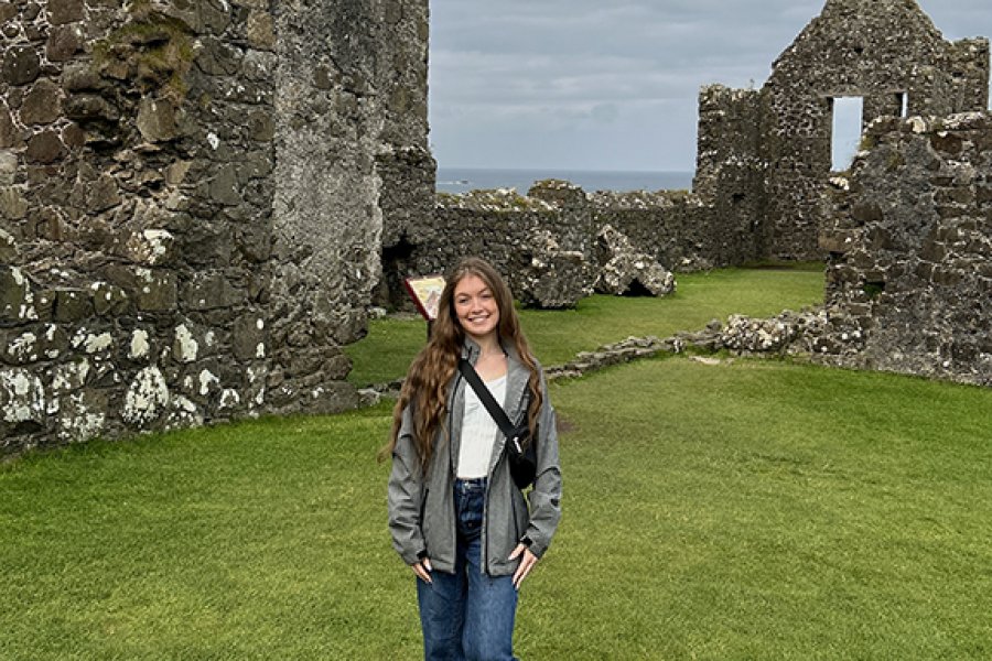 A student standing in front of a ruined historical castle