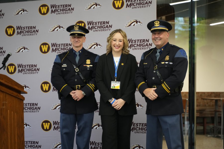Shelby Wilmot stands on a stage between two MSP troopers.