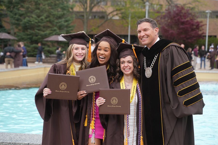 President Kavalhuna celebrates with spring 2026 graduates at commencement outside.