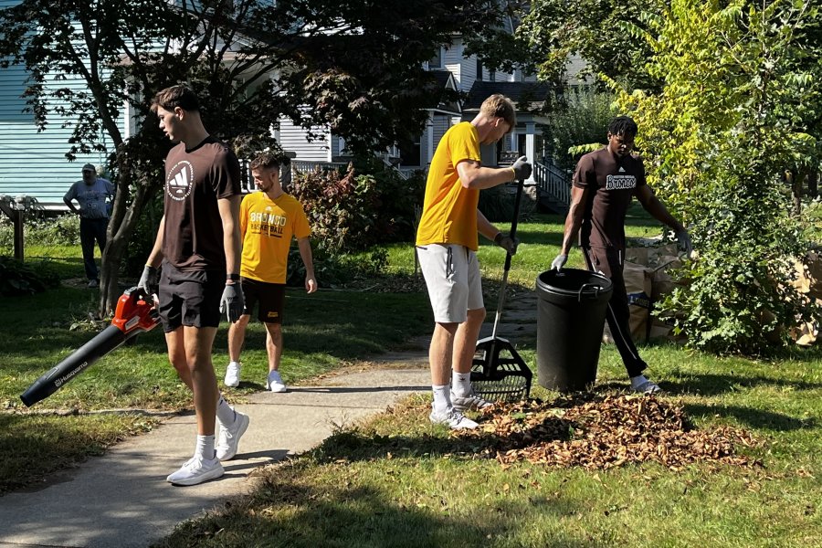 WMU Men's Basketball players, volunteering in the Vine Neighborhood, working on neighborhood cleanup with Building Blocks of Kalamazoo.
