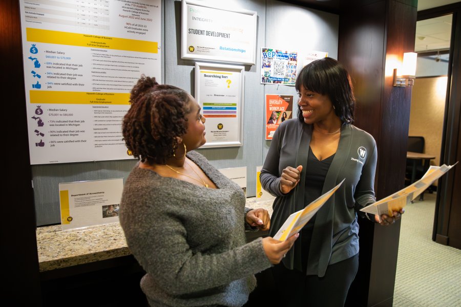 Two women look at paperwork together in a Western hallway.