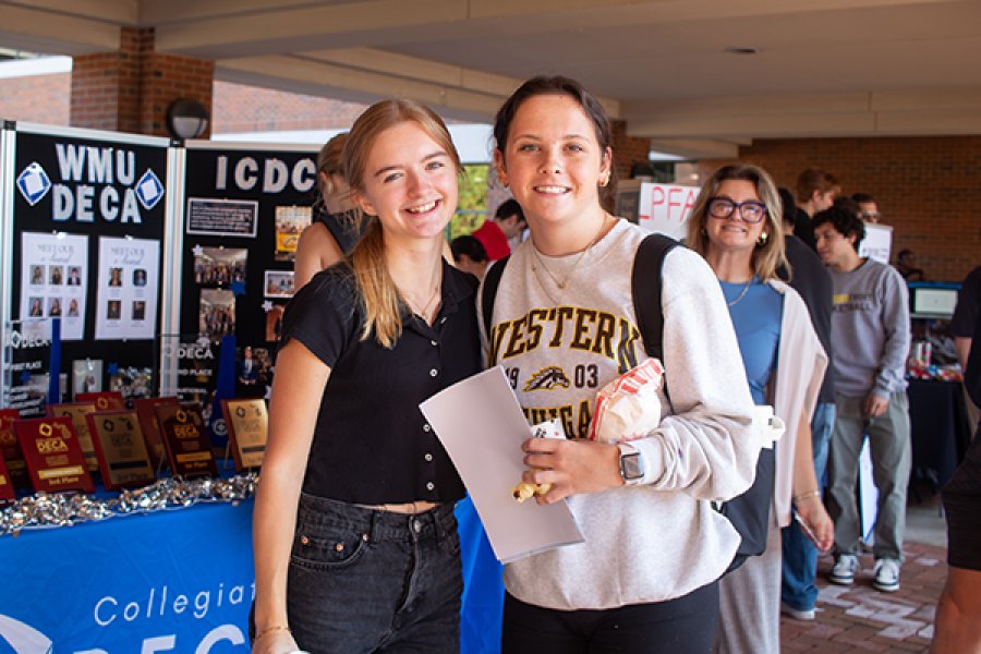 Two students in front of a student organization sign at business bash
