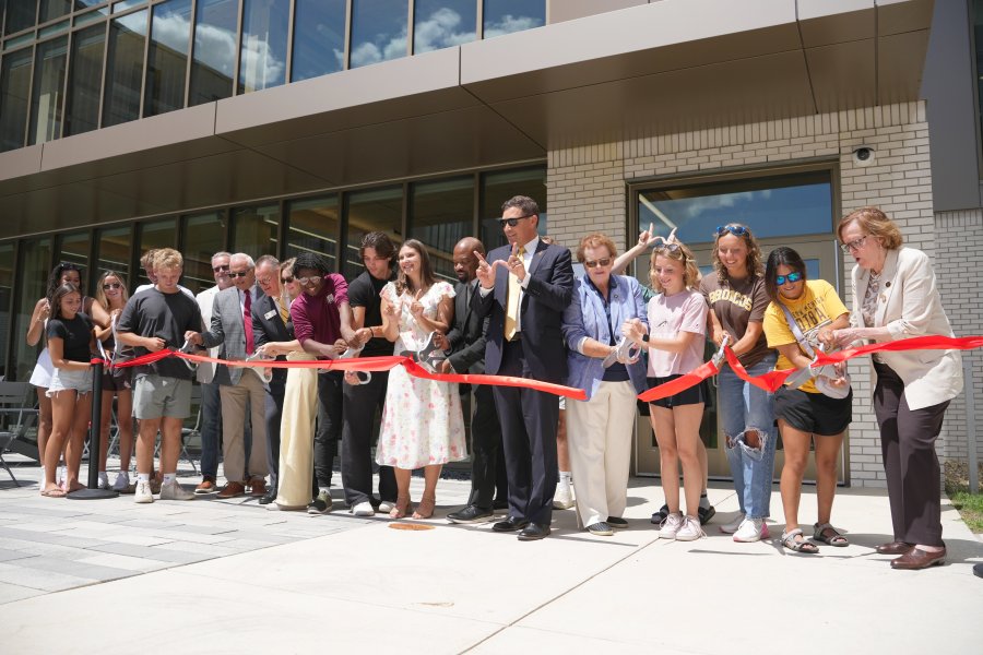 WMU officials and students cut a red ribbon in front of Valley Oaks residence hall.