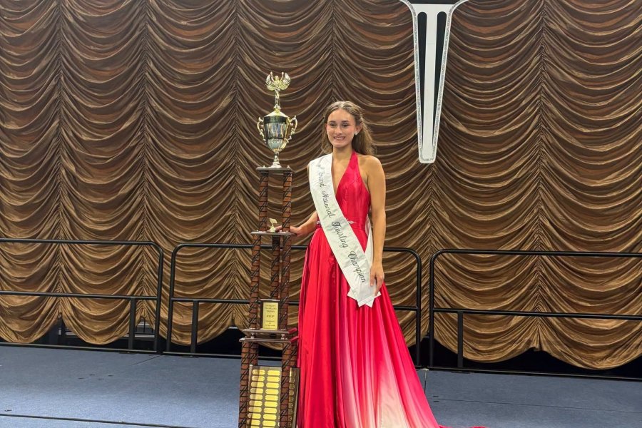 Emily Brown wearing an evening gown standing next to her Twirling trophy.