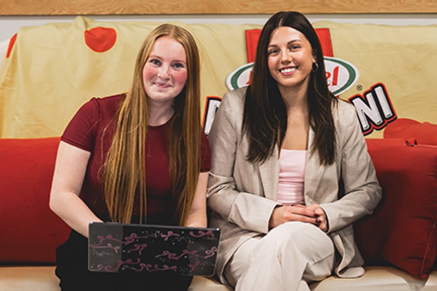 Two students sitting on a hot dog couch looking at food marketing opportunities 