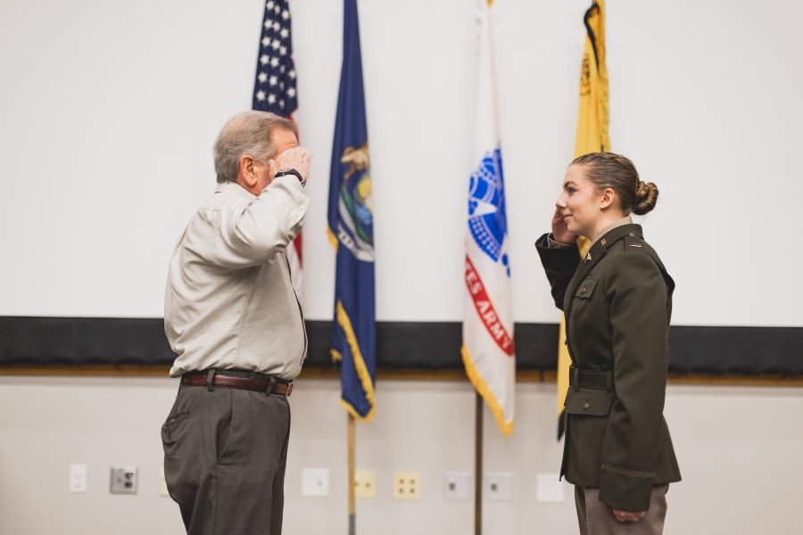 Molly Cochran being sworn in to her commission by a man, their right hands are raised as they face each other.