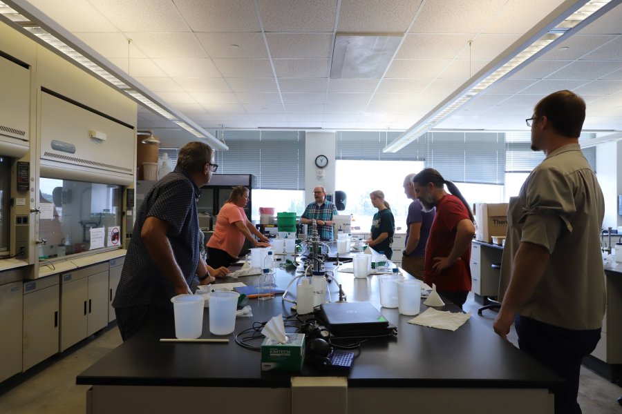 group of people gathered around a large table in a lab