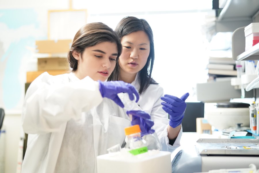 two females in lab coats test a sample