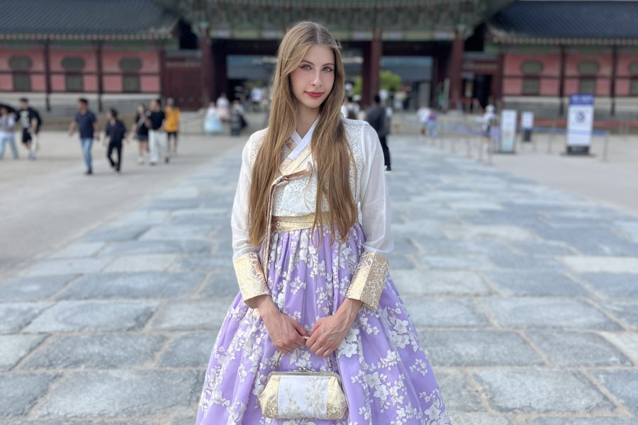 WMU study abroad student studies abroad in Korea. She is wearing traditional clothing and standing in front of an old Korean building. 
