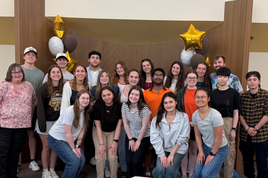 Honors advisor Kerrie Harvey stands with the Peer Student Success Team mentors in the honors college lounge.