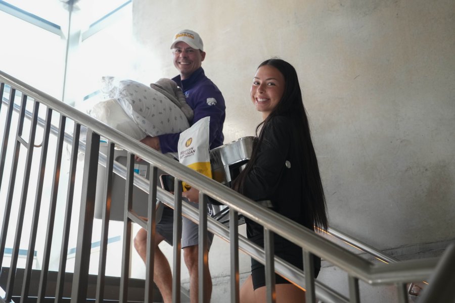 A dad and daughter carry items upstairs.