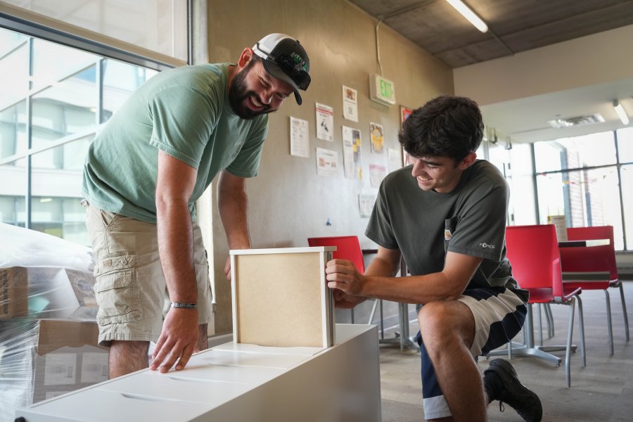 A dad and son assemble furniture.