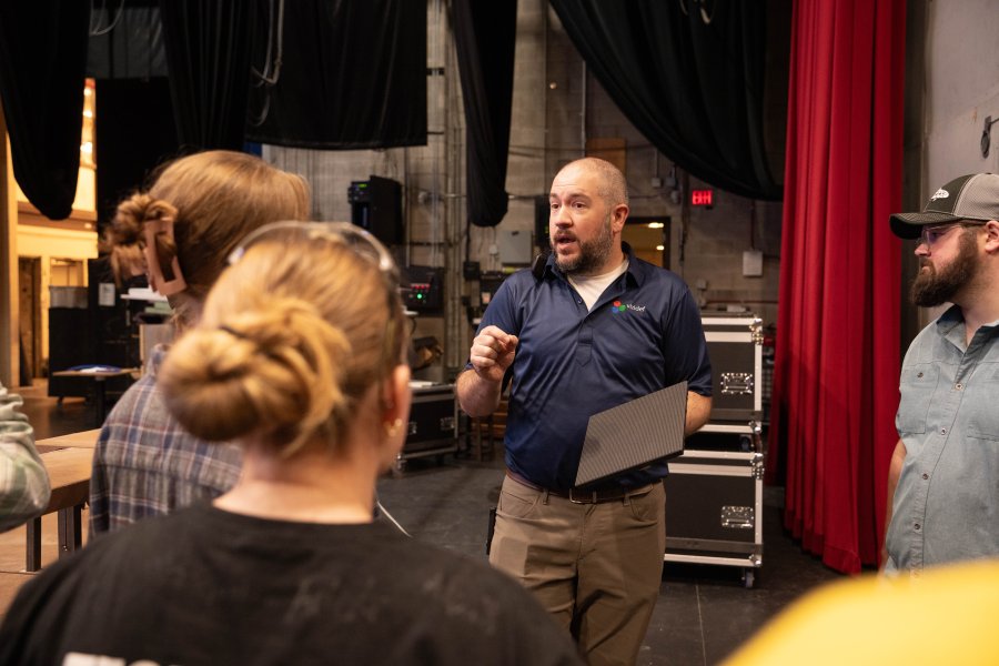 A technician talks to a group of students in the theater.