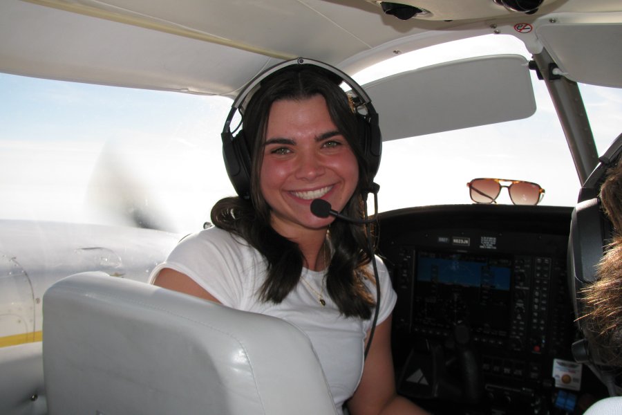 Student with headset in front seat of plane.