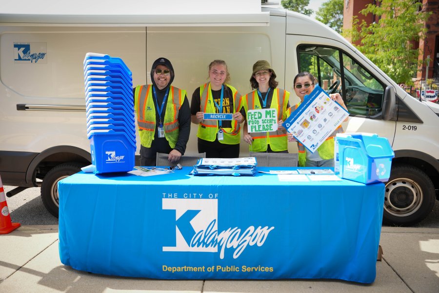A group of people stands at a City of Kalamazoo table.