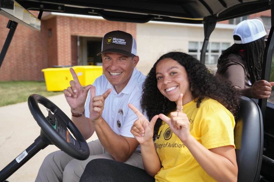 President Russ Kavalhuna and a student sit in a golf cart.