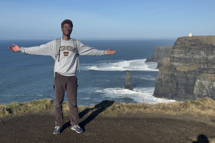 WMU study abroad student stands on the cliffs in Ireland while holding his arms out. 