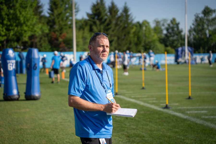 Senior writer Tim Twentyman stands with pencil and paper in hand, observing a Detroit Lions practice.