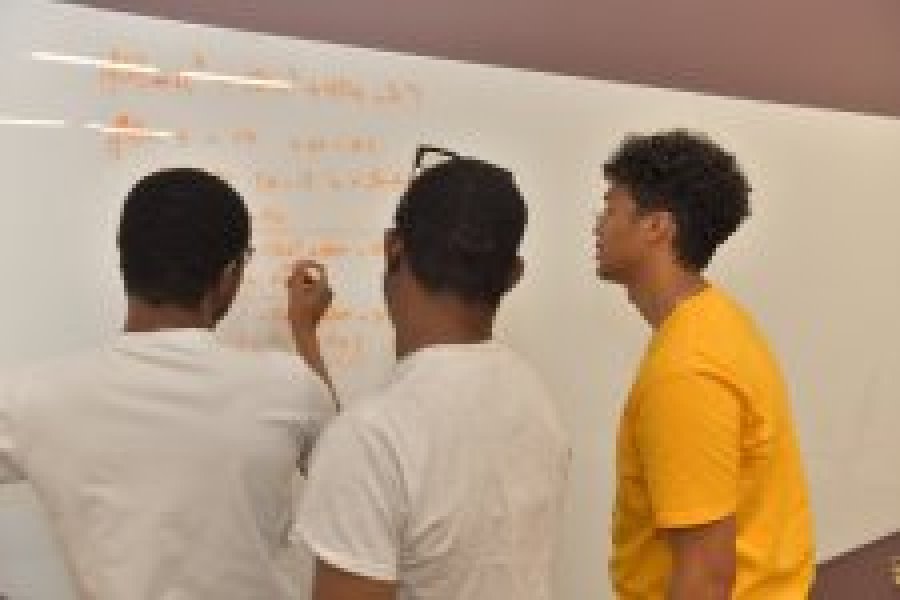 Students working a math problem on a white board
