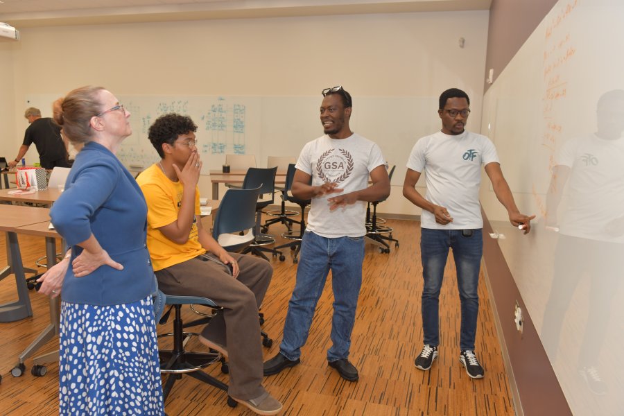 faculty and students discussing a problem on the board