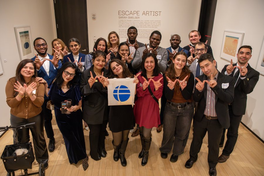 Members of Western's Fulbright community pose in a group and make "W" hands to celebrate Western. They hold a Fulbright sign at a University event.
