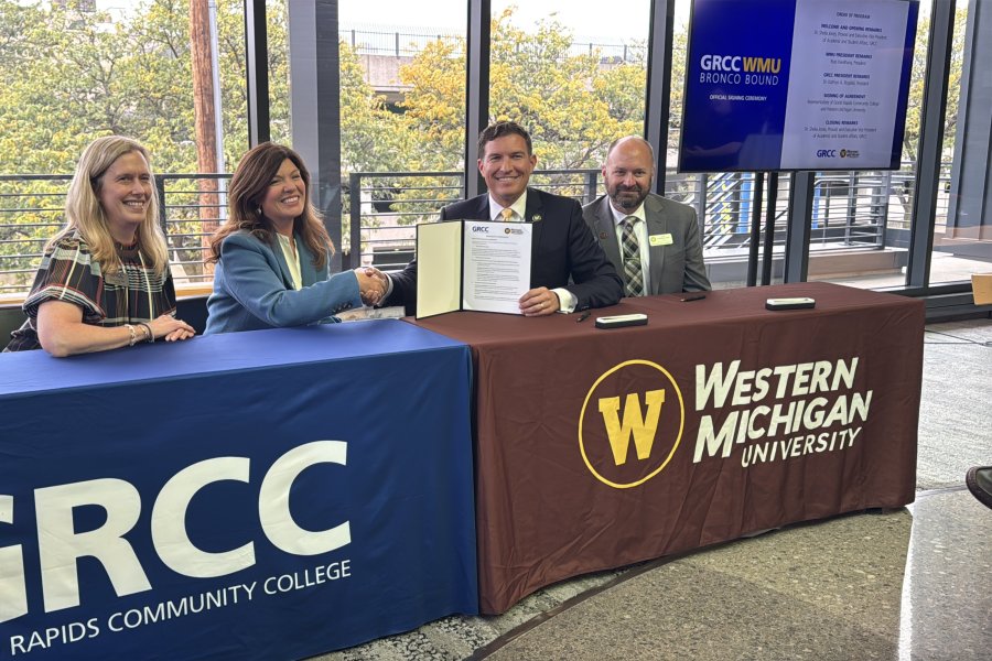 WMU and GRCC leaders sit at a table and sign an agreement.