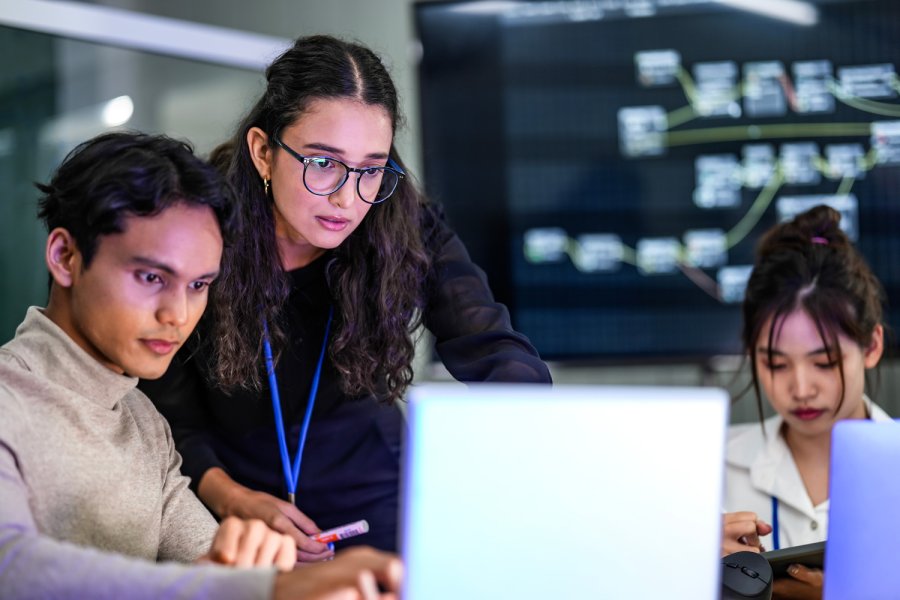 Three professionals around a laptop