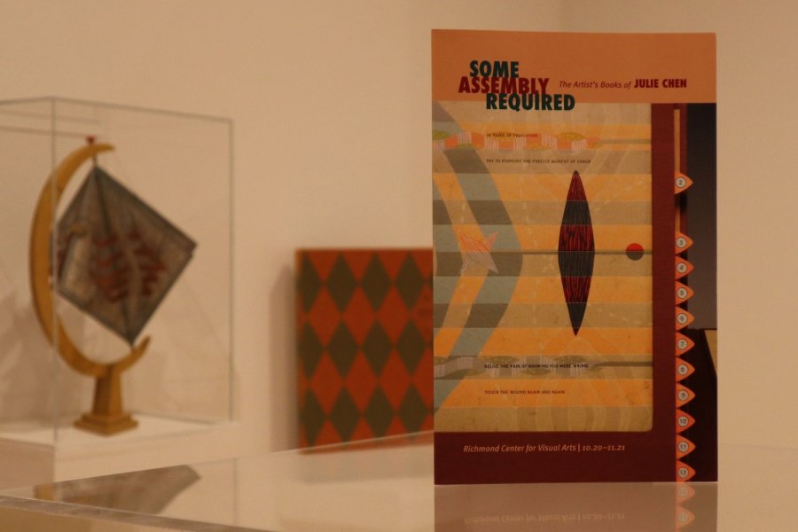 "Some Assembly Required" book by Julie Chen in the foreground with other book arts displayed in an exhibit behind.