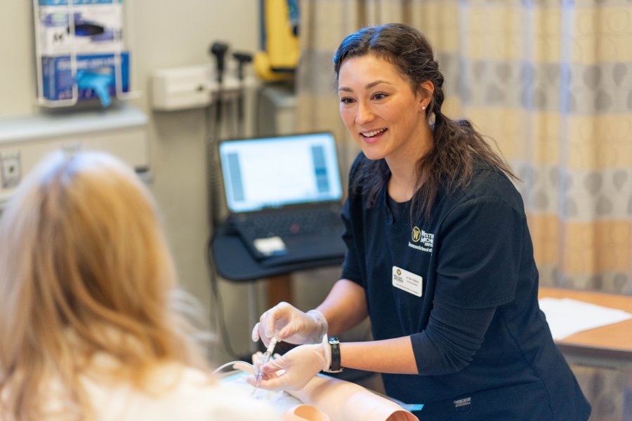 A Bronson School of Nursing student practicing an injection with a professor.