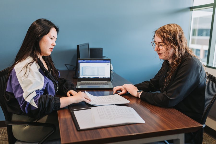 Two people seated at a desk looking over papers