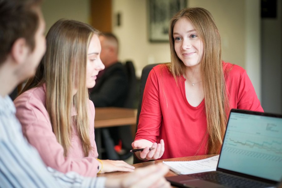 Food marketing student Lily Zwanka with two fellow business students seated at a table