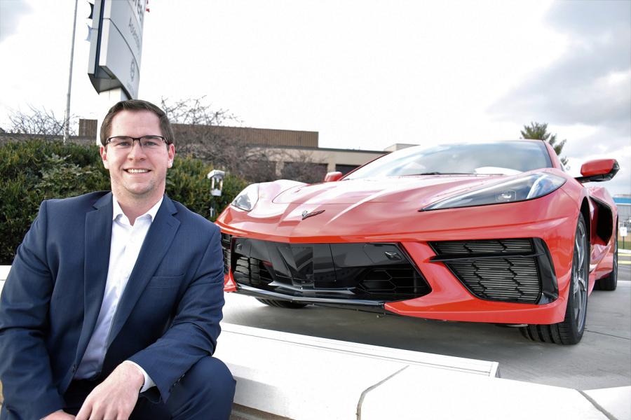 Pictured is Steven Ross sitting in front of a red car