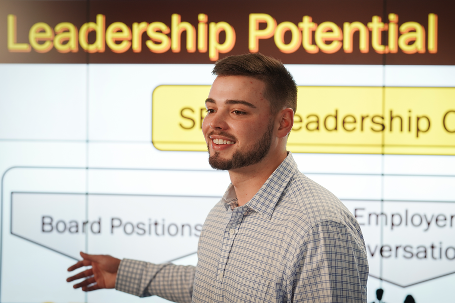 Sales and business marketing student presenting in front of a screen.