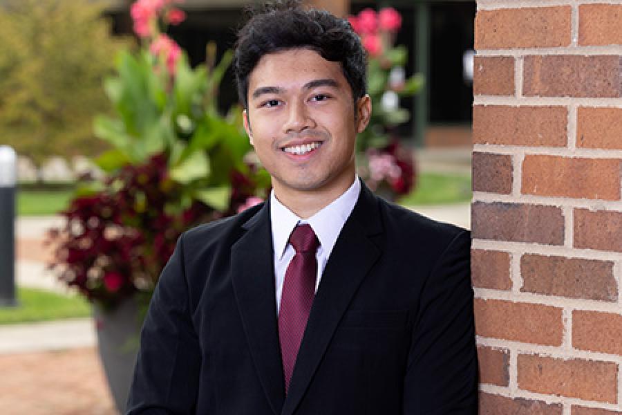 Crizio Sinuraya in a business suit with the WMU Haworth courtyard in the background.