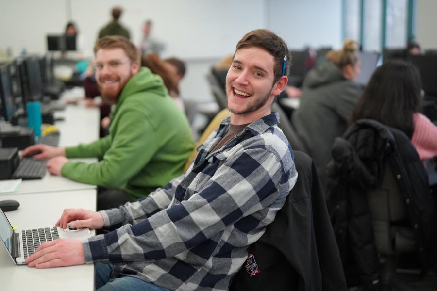 male student smiling in a classroom.