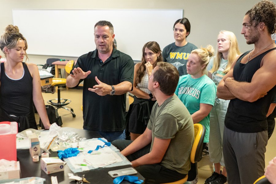 Students listening to a professor in a health lab.