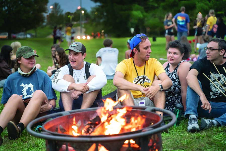 Students during orientation gathered around a fire pit.