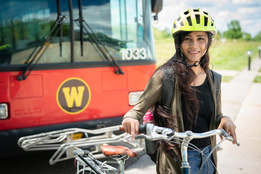 Student on her bike in front of a Metrol bus.