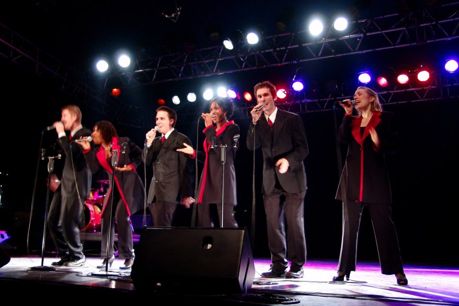 Gold Company on stage with lights behind them, singing. Performance from about 15 years ago.